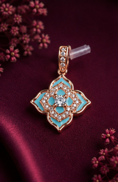 A gold-tone floral pendant with turquoise enamel and clear stones, displayed on a deep burgundy satin fabric with small pink flowers in the corners.