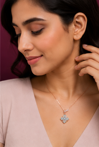 A close-up lifestyle shot of a woman wearing a delicate rose gold necklace with a geometric pendant featuring light blue stones, set against a dark plum background.